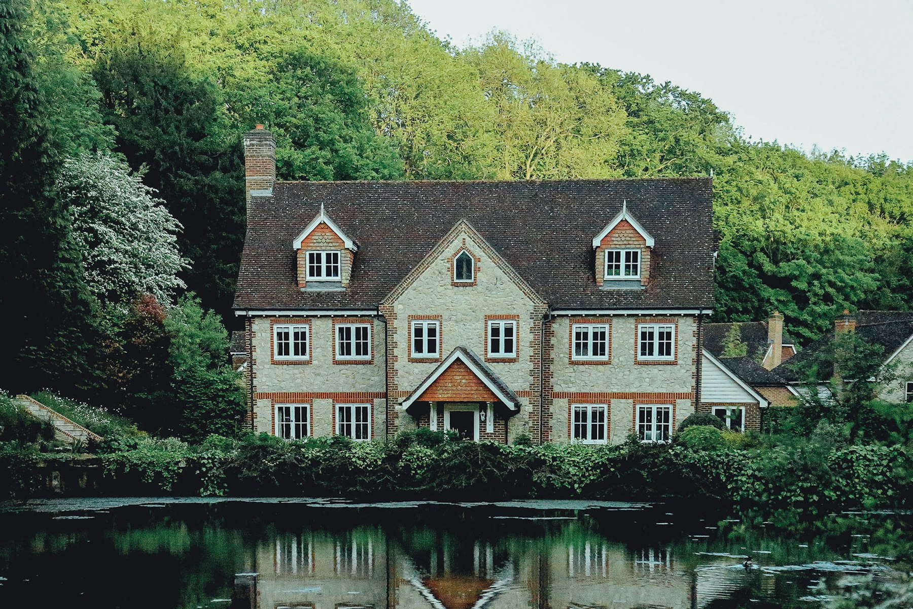 The stone house across the water, trees at its back